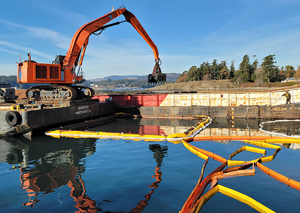 Photo of orange dredge equipment mounted on a barge on the waterway.