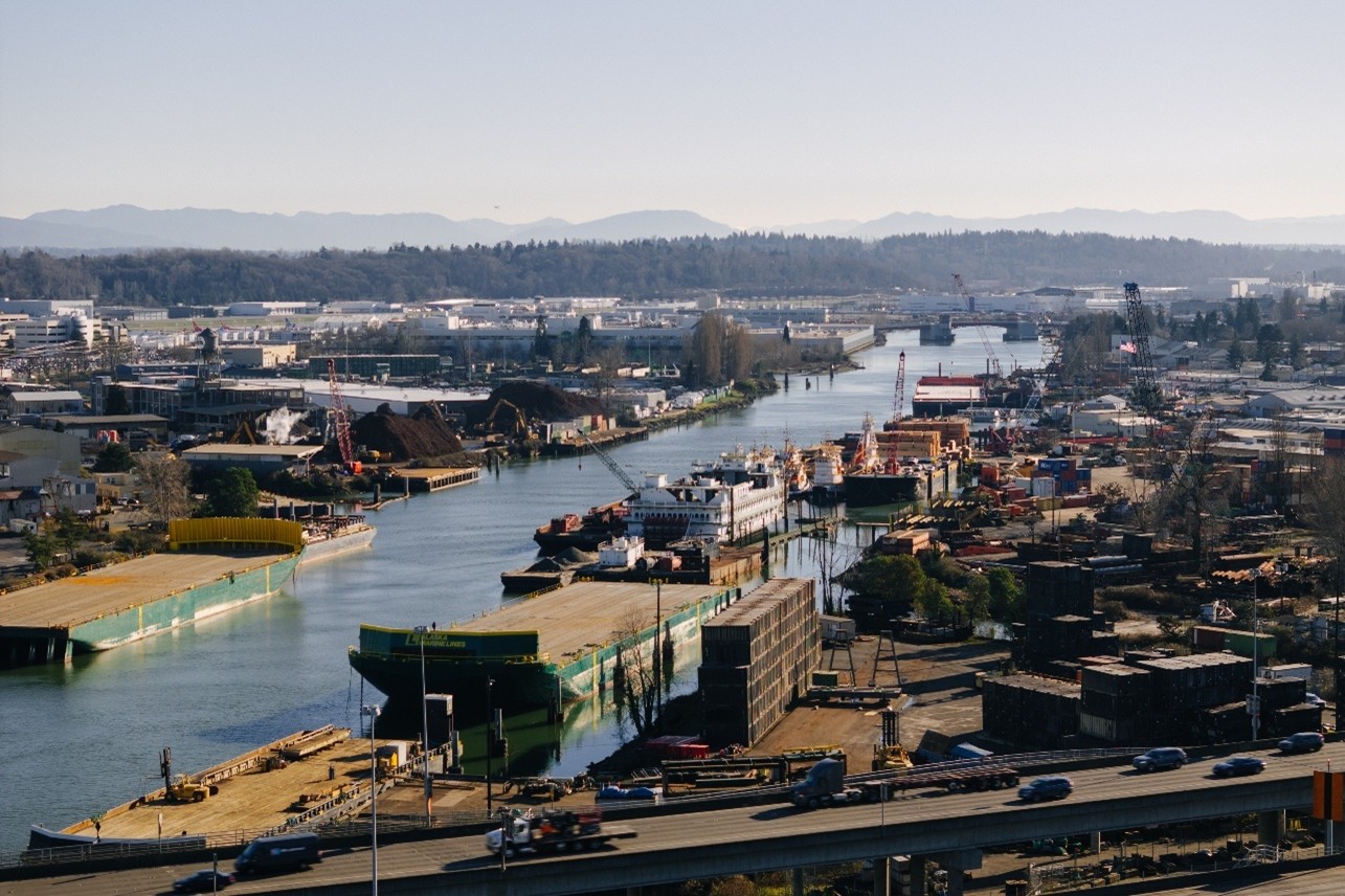 Photo of the Lower Duwamish Waterway middle reach, looking south east. Photo shows barges, vessels, and maritime activity along the river and South Park Bridge in the distance.